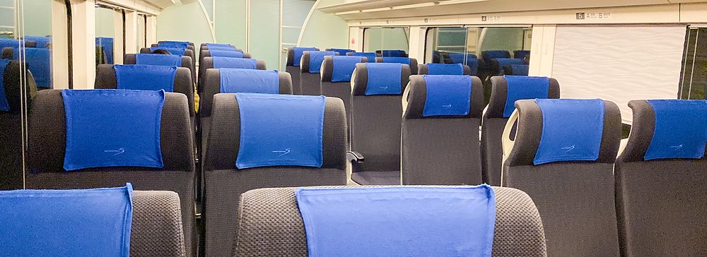 Interno del treno Skyliner con sedili neri e poggiatesta blu.