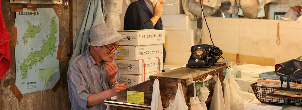 Due uomini lavorano all'interno di una bottega nel vecchio mercato del pesce di Tsukiji a Tokyo.