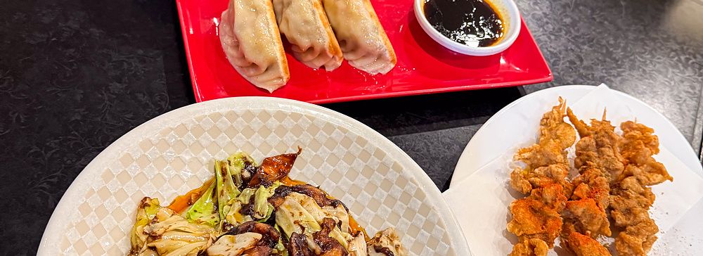 Verdure saltate con carne di soia, spiedini di carne di soia e gyoza su un tavolo al ristorante Sairaien di Ueno.
