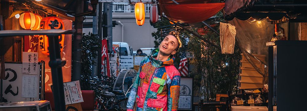 Marco Togni con abiti colorati sta sotto le lanterne accese in un vicolo in Giappone.