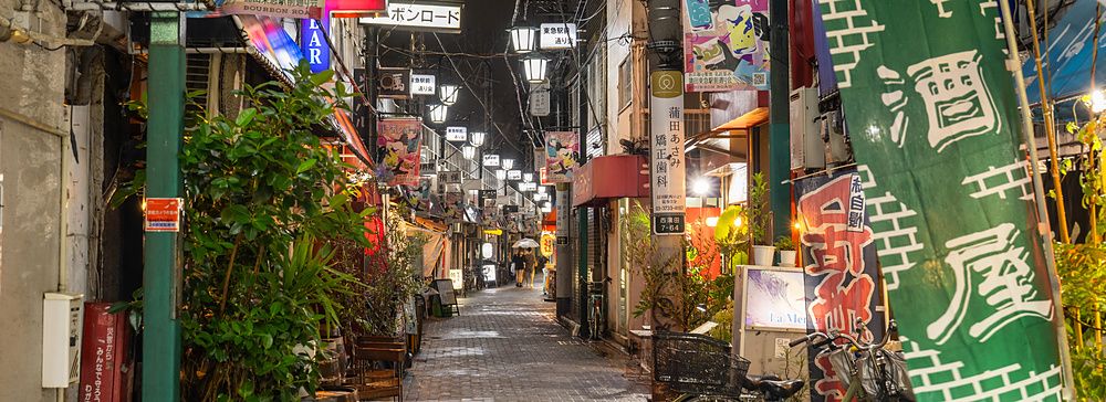 Vicolo stretto e suggestivo a Kamata, Tokyo, illuminato da insegne al neon e lanterne durante la notte.