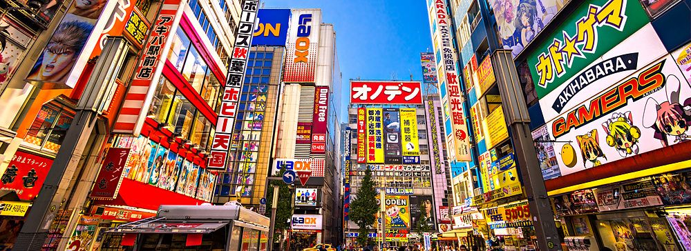 Strada colorata di Akihabara, Tokyo, con cartelloni di anime e tecnologia.