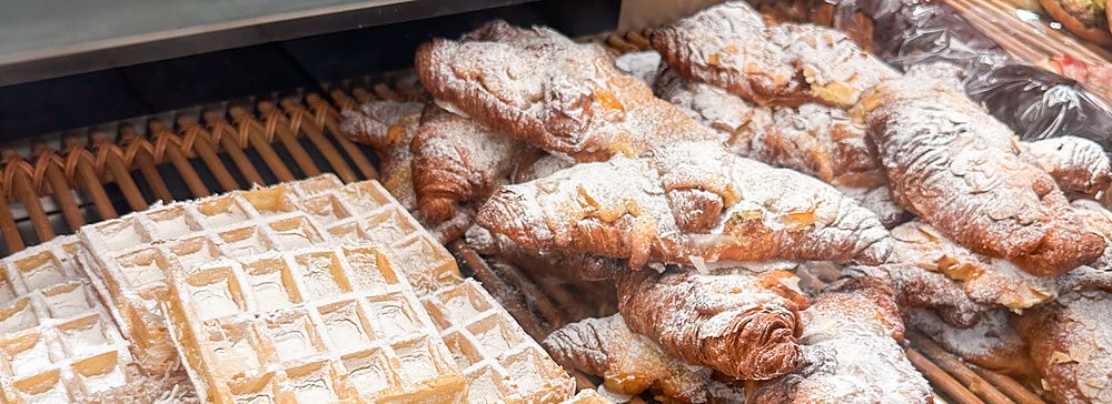 Vetrina di una panetteria Paul in Giappone con waffle al cocco e croissant cosparsi di zucchero a velo.