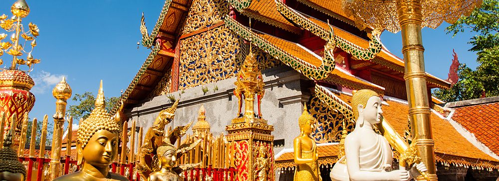Il Wat Phra That Doi Suthep a Chiang Mai con statue dorate sotto un cielo blu.