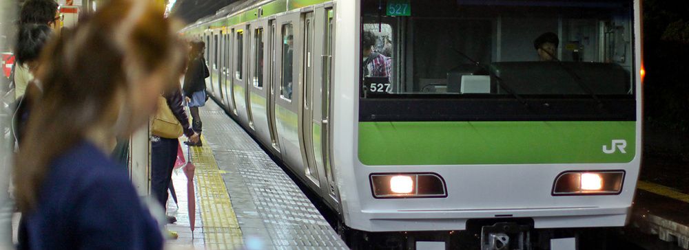 Treno della linea Yamanote in Giappone con una persona sul binario