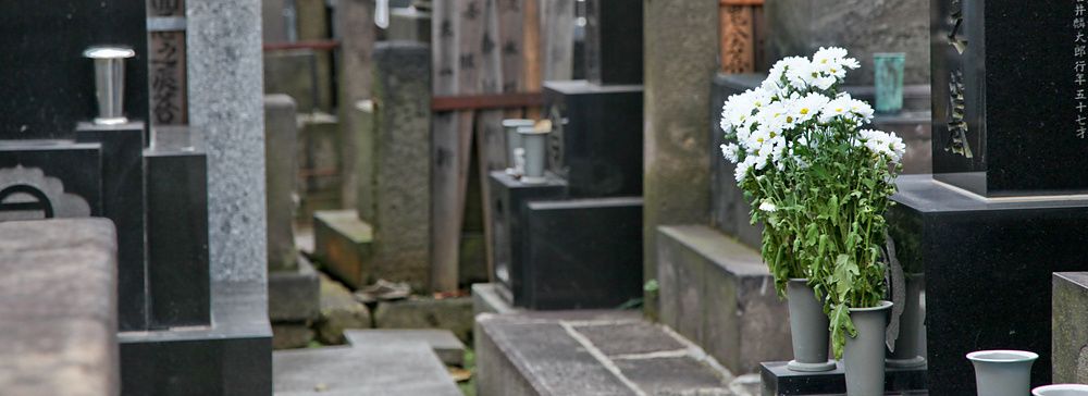 Cimitero tradizionale giapponese con fiori bianchi a Yanaka.