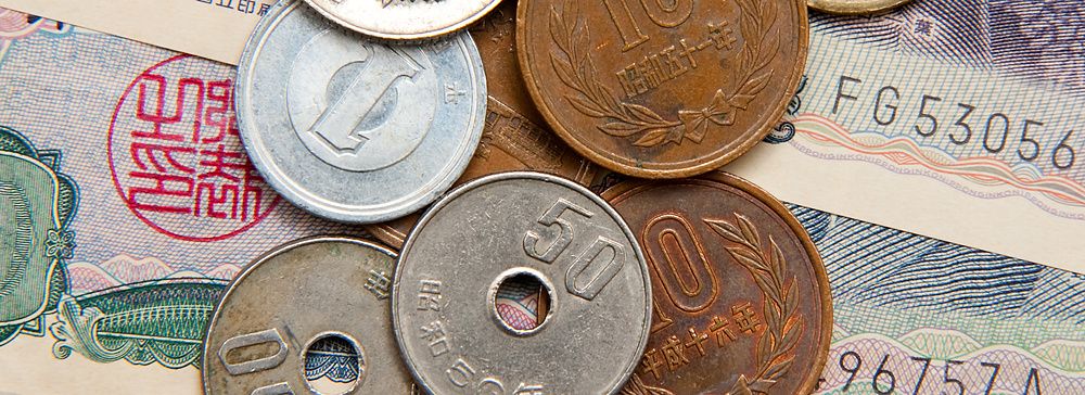 Diversi yen giapponesi in monete e banconote su una superficie.