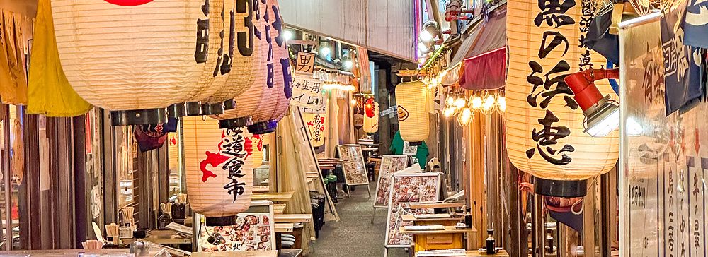 Via stretta con lanterne e tavoli nei ristoranti di Yurakucho Yokocho.