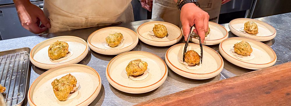 Impiattamento delle zeppoline con funghi a Mushroom Tokyo con chef al lavoro su un bancone in acciaio.