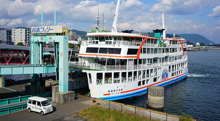 Il traghetto Sakurajima attraccato al molo di Kagoshima con un furgone bianco sulla banchina.