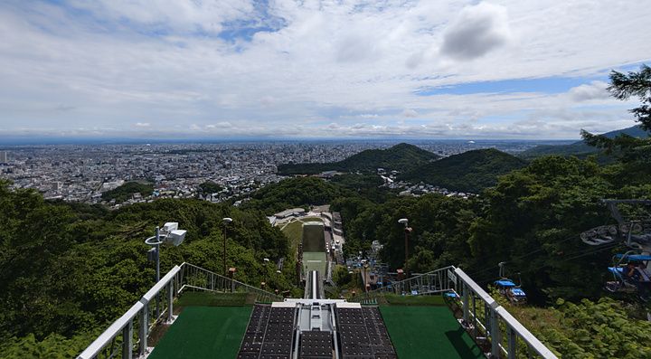 Veduta grandangolare della città di Sapporo vista dalla cima del trampolino olimpico di Okurayama in una giornata estiva.