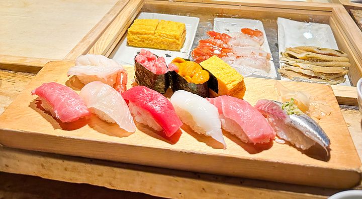 Uno chef prepara il pesce dietro il bancone presso il ristorante Tsukiji Itadori Bekkan, con nigiri sushi in primo piano.