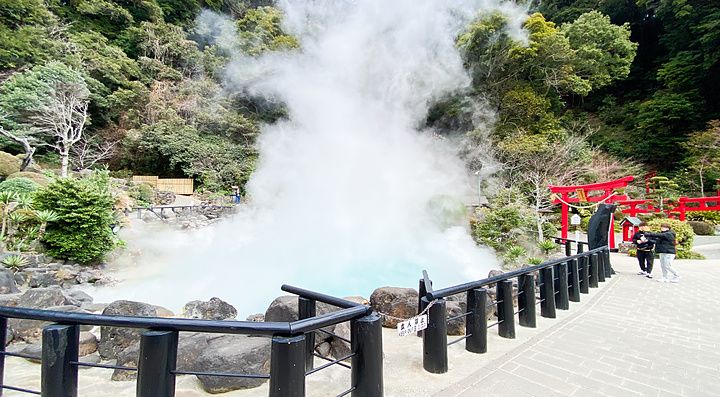 L'Umi Jigoku a Beppu con vapore denso che si alza dalla vasca azzurra accanto a un portale torii rosso.
