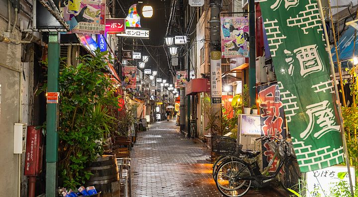 Vicolo stretto e suggestivo a Kamata, Tokyo, illuminato da insegne al neon e lanterne durante la notte.