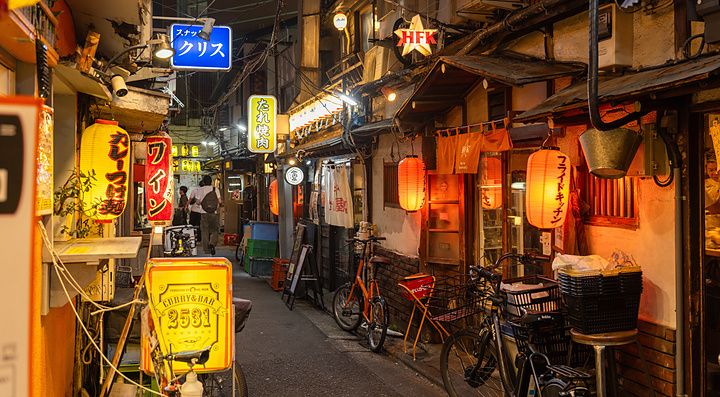 Vicolo notturno a Sangenjaya, Tokyo, con lanterne accese, insegne di locali e biciclette parcheggiate.