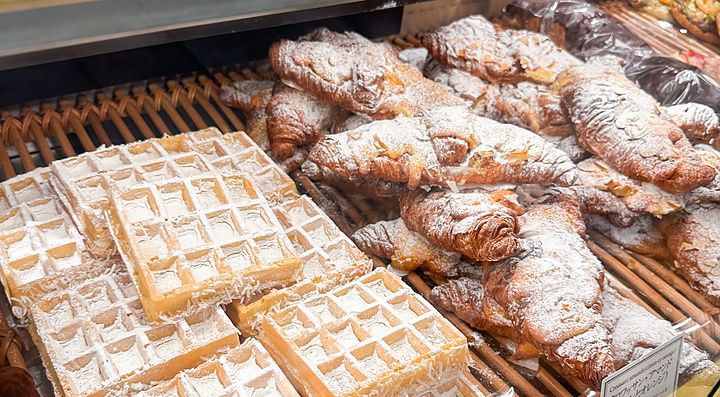 Vetrina di una panetteria Paul in Giappone con waffle al cocco e croissant cosparsi di zucchero a velo.