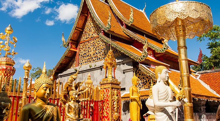 Il Wat Phra That Doi Suthep a Chiang Mai con statue dorate sotto un cielo blu.