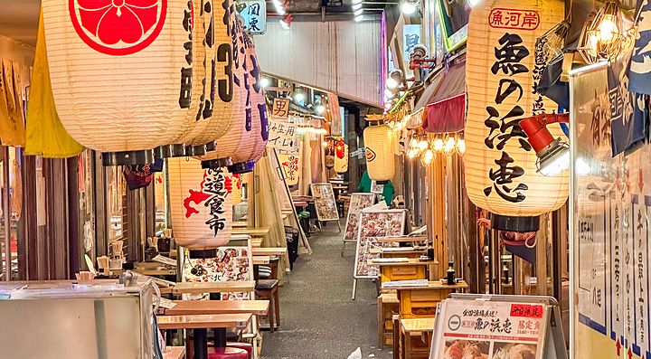 Via stretta con lanterne e tavoli nei ristoranti di Yurakucho Yokocho.