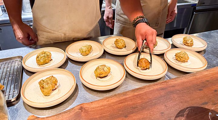 Impiattamento delle zeppoline con funghi a Mushroom Tokyo con chef al lavoro su un bancone in acciaio.