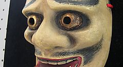 Maschera teatrale tradizionale con occhi spalancati e dettagli espressivi.
