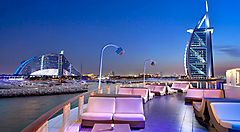 Tavoli in un ristorante all'aperto a dubai, al tramonto, con in lontananza la "vela di Dubai".