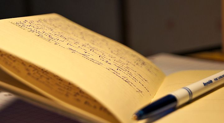Un quaderno aperto con appunti scritti a mano e una penna a inchiostro.