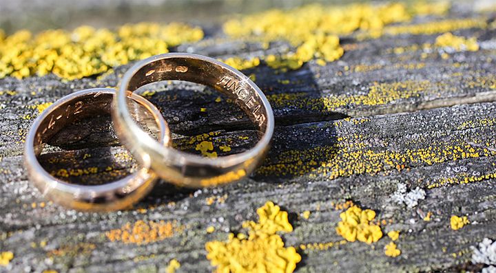 Due fedi nuziali su un tavolo di legno con lichene giallo.