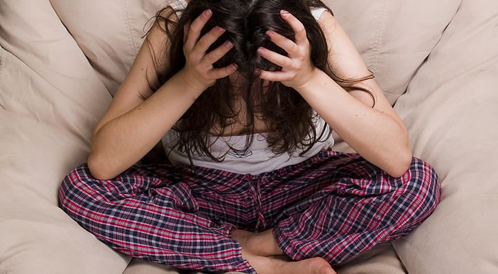 Una ragazza seduta, si dispera con le mani tra i capelli.