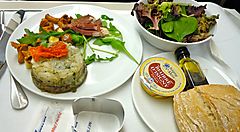 Piatto di cibo gourmet con insalata mista e pane su un vassoio.