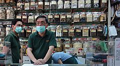 Interno di una farmacia tradizionale asiatica con tre persone al banco.