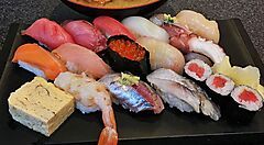 Una varietà di sushi su un piatto nero al ristorante Sushi Zanmai.