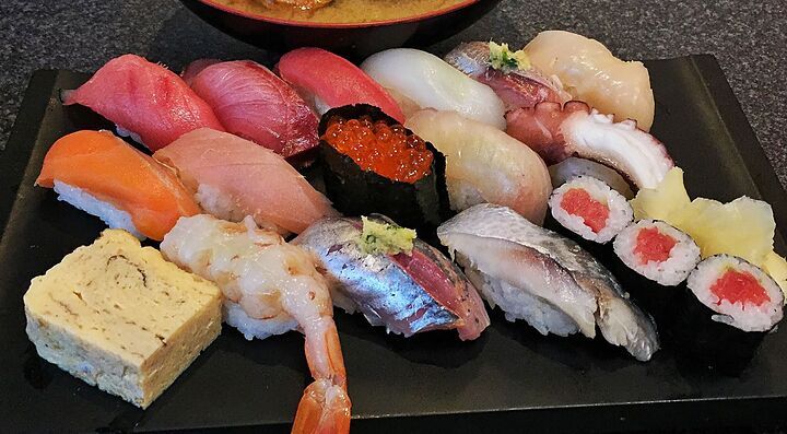 Una varietà di sushi su un piatto nero al ristorante Sushi Zanmai.