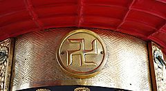 Simbolo swastika dorato su fondo rosso decorato.
