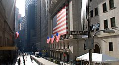 Gioco di ombre e luci a Wall Street, con varie bandiere USA.