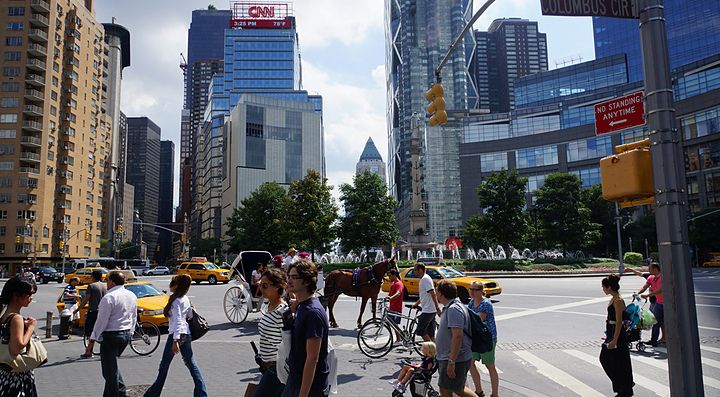 Pedoni incrociati a Times Square, New York, con grattacieli sullo sfondo.