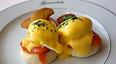 Uova Benedict su piatto con salmone e patate al forno.