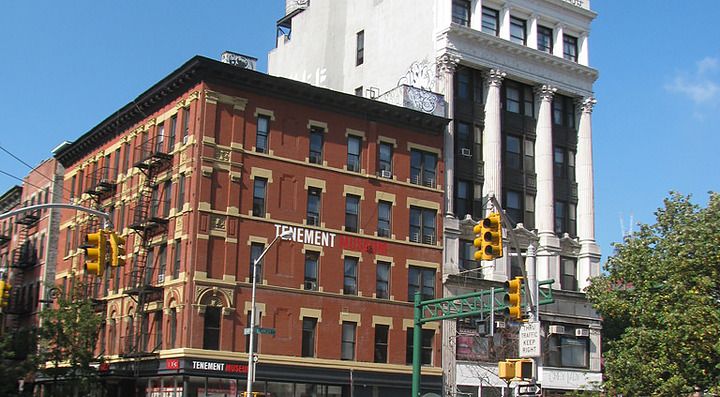Incrocio trafficato con edifici storici e vegetazione urbana.