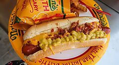Hot dog Nathan's con formaggio e pancetta su piatto di carta.
