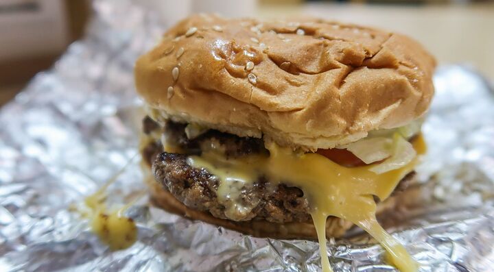 Hamburger di Five Guys con formaggio fuso e cipolle su un foglio di alluminio.