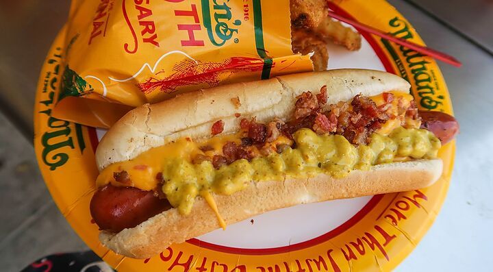Hot dog Nathan's con formaggio e pancetta su piatto di carta.