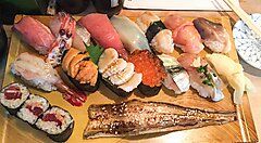 Vari tipi di sushi assortiti su un piatto di legno.