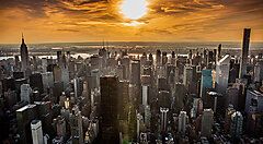 Tramonto sulla skyline di una New York con numerosi grattacieli e cielo arancione.