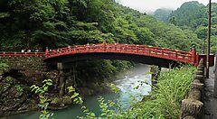 Il ponte Shinkyo a Nikko tra fitta vegetazione e un fiume.