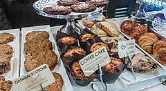 Vetrina di dolci e biscotti assortiti in una pasticceria, tra cui muffin e croissant.