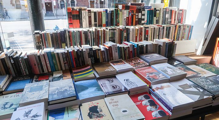 Libri esposti su tavoli in una libreria ben illuminata.