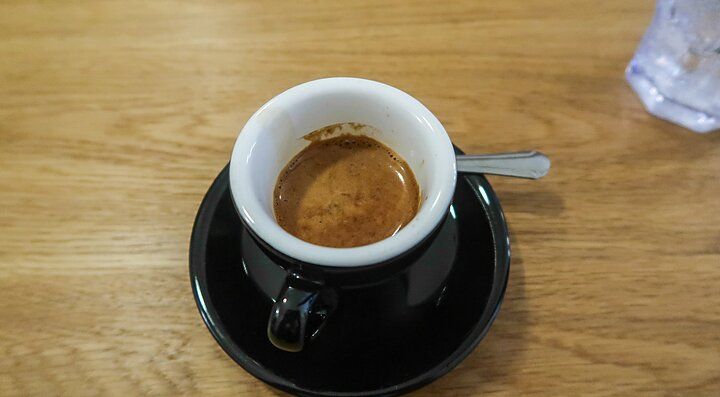 Tazzina di caffè espresso su piattino nero al Cafe Grumpy.