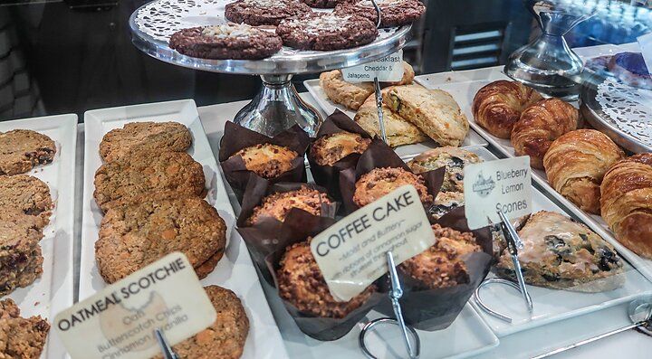 Vetrina di dolci e biscotti assortiti in una pasticceria, tra cui muffin e croissant.