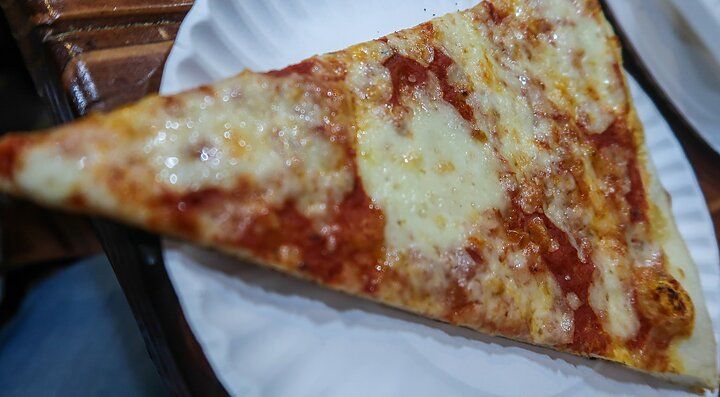 Fetta di pizza margherita su un piatto di carta.