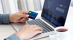 Una persona con una carta di credito in mano sta facendo acquisti online.