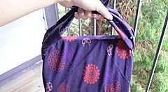 Una mano tiene una borsa furoshiki viola con motivi floreali rossi.